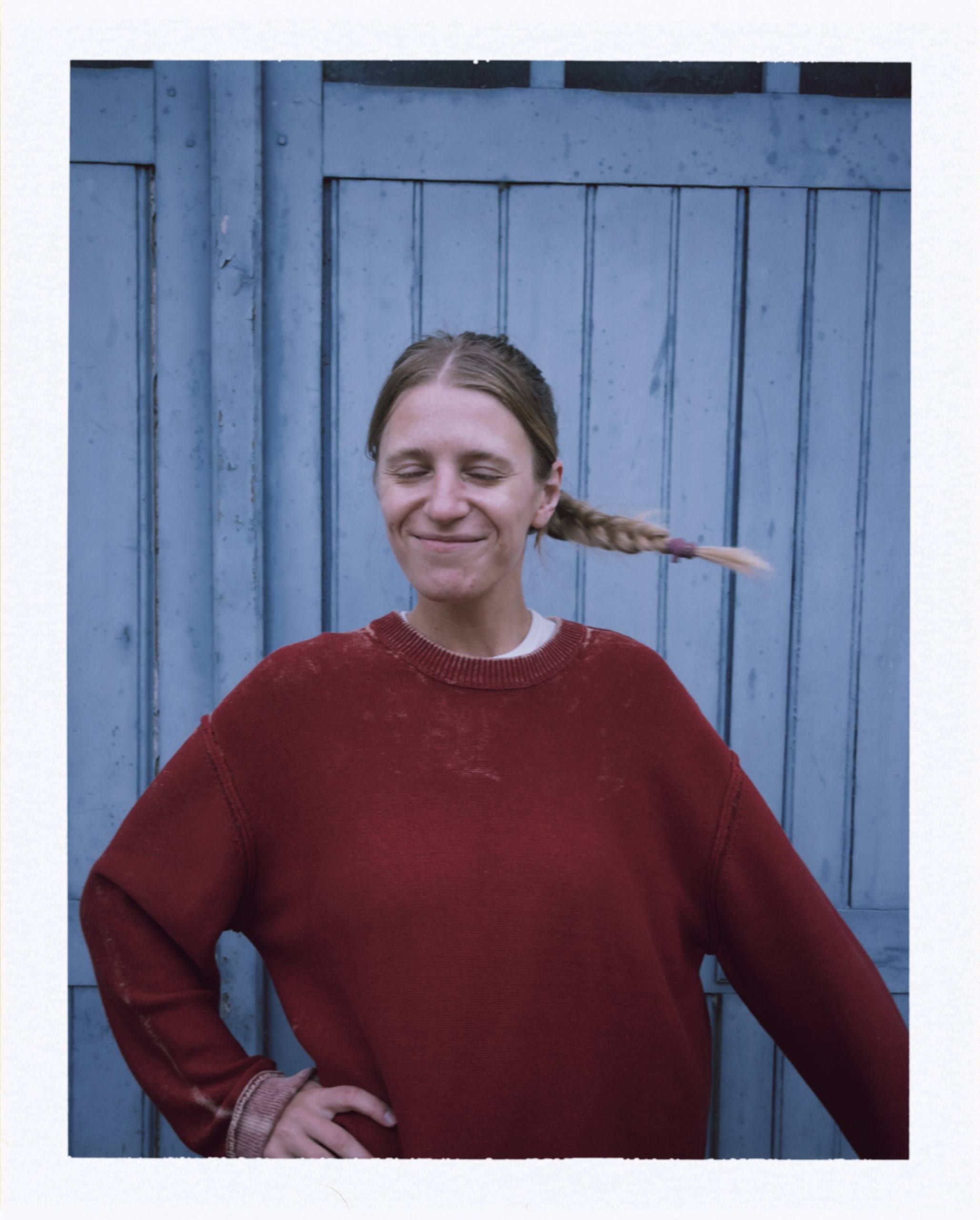 Liza smiling in front of a blue wooden wall