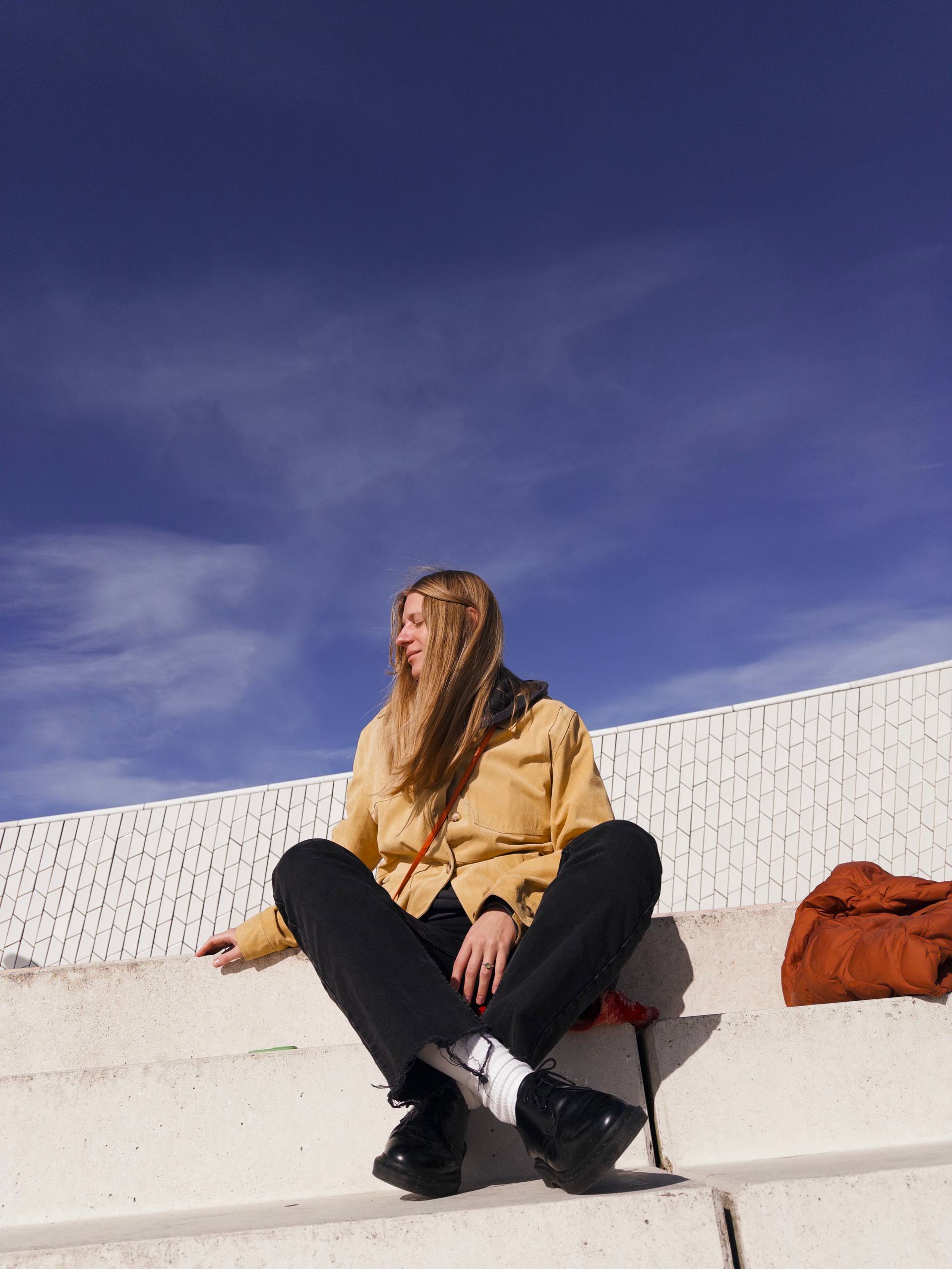 Liza sitting in bright sunlight beneath a deep blue sky