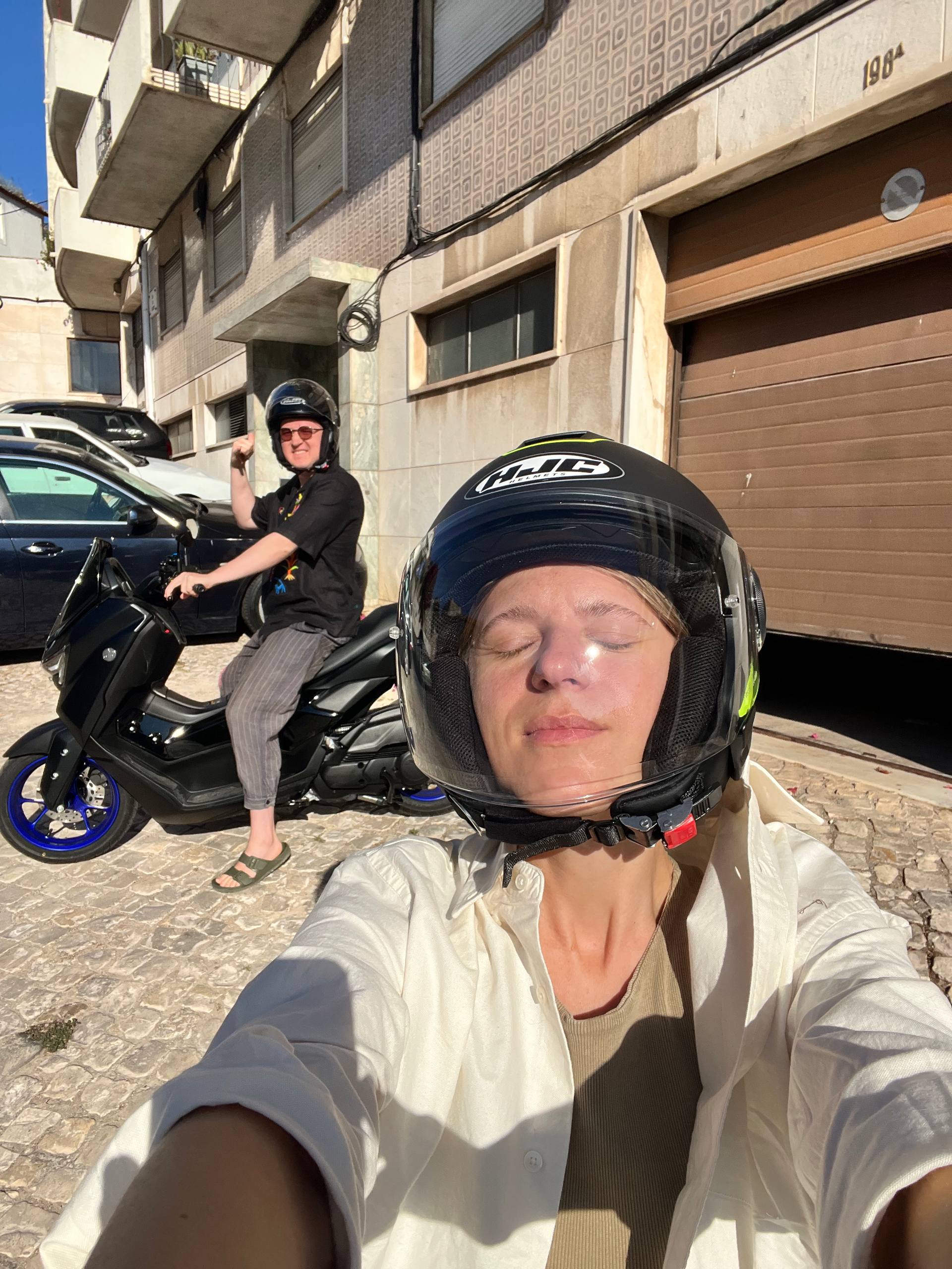 Liza and Ruslan wearing scooter helmets in the sun